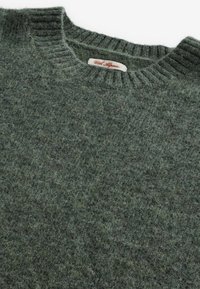 Pull en tricot gris-vert fabriqué en douce laine d'alpaga, avec un col rond côtelé et une texture duveteuse. Étiquette visible à l'intérieur du col.