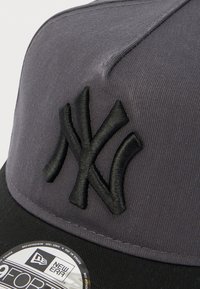 Γκρι καπέλο με μαύρο κεντημένο λογότυπο των New York Yankees. Διαθέτει δομημένη κορώνα, επίπεδη γείσο και ετικέτα στην κάτω πλευρά της γείσου.