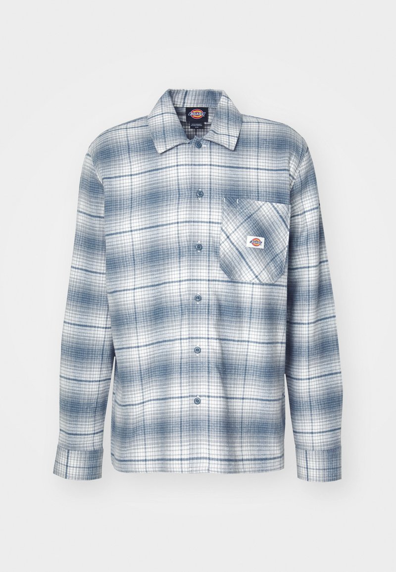 Camicia a quadretti blu e bianca con bottoni, caratterizzata da maniche lunghe, una tasca sul petto e un'etichetta con logo vicino alla tasca. Materiale in cotone.