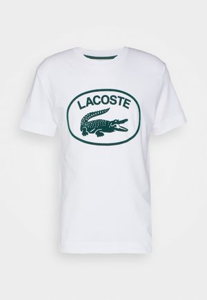 Weißes T-Shirt mit kurzen Ärmeln und dunkelgrünem Lacoste-Logo mit einem Krokodil in einem Oval auf der Brust.