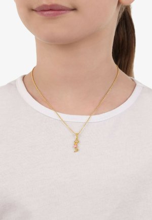 Goldkettchen mit einem Anhänger, der ein pinkes Blumenmuster zeigt. Getragen über einem weißen T-Shirt, das einen zarten, einfachen Stil zur Geltung bringt.