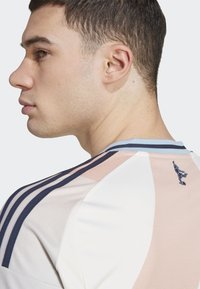 Jersey desportivo masculino com um tecido suave e texturizado, com blocos de cores rosa, branco e azul-marinho, ombros risca e um pequeno detalhe de logótipo nas costas.