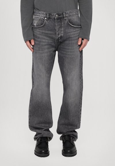 Jeans din denim gri cu o croială lejeră, având un finisaj uzat, cinci buzunare și închidere cu nasture. Asortate cu cizme negre.