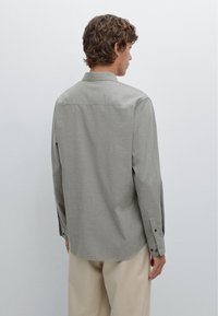 Grijs langemouwen shirt van een gestructureerde stof, met een rugpiep en knoopmansjetten. Draag het met beige broeken, met een recht model.