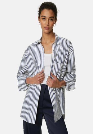 Witte overhemd met blauwe verticale strepen, met een relaxte pasvorm, lange mouwen en een borstzak. Gedragen over een witte tanktop.