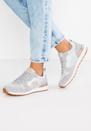 Gray athletic shoes with a combination of mesh and suede materials, featuring a light-colored sole, textured accents, and a branding logo.
