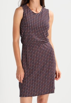 Robe sans manches longueur genou avec une base bordeaux et un petit motif floral portée par une femme debout sur un fond uni.