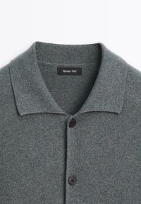 Grijze gebreide cardigan met een platte kraag, voorzien van twee zwarte knopen en een label genaamd "Massimo Dutti" dat in de halslijn is genaaid.