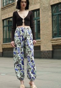 Top castanho cropped combinado com calças jogger largas e estampadas em verde claro, azul e preto, com cintura elástica e bainhas ajustadas.