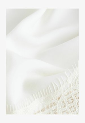 Material alb cu textură netedă, având detalii din dantelă pe margine și o franjură subțire, îmbinând eleganța delicată cu modele fine.