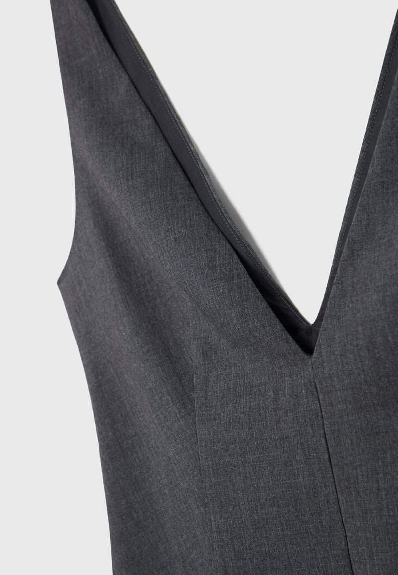 Abito grigio asimmetrico con profondo scollo a V, tessuto testurizzato e linee pulite, con cuciture visibili e un leggero lucido.