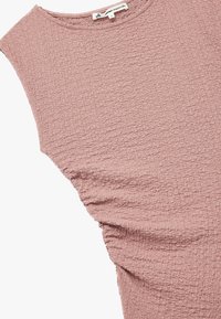 Top sin mangas de color rosa empolvado, con una tela texturizada y arrugada, que presenta un escote redondo y un detalle fruncido en los laterales para una silueta ajustada.