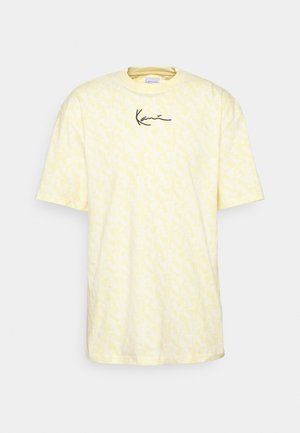 Gelbes Baumwoll-T-Shirt mit durchgehendem Muster und schwarzem Signaturlogo auf der Brust, runder Ausschnitt und kurze Ärmel.