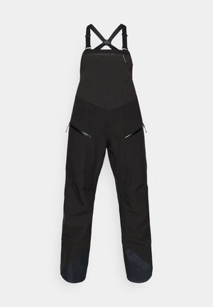 Macacão de esqui preto com parte superior ajustada e pernas largas. Apresenta alças ajustáveis, bolsos laterais com fecho e tecido escuro em contraste nos tornozelos.