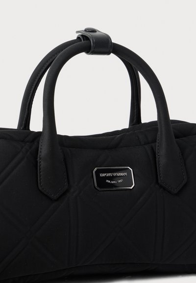 Μαύρη καπιτονέ τσάντα χειρός με διπλές λαβές και μικρή μεταλλική πινακίδα με το λογότυπο Emporio Armani στο μπροστινό μέρος.