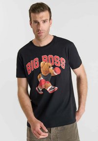 Camiseta de algodón negra con un gráfico de un oso con guantes de boxeo, con el texto "BIG BOSS" arriba en letras rojas en negrita. Cuello redondo.