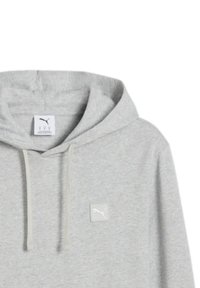 Sudadera gris claro con bolsillo estilo canguro, capucha con cordón y un pequeño parche de logo blanco en el pecho. Fabricada con un tejido suave y texturizado.