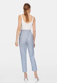 Pantalon rayé bleu et blanc, taille haute, coupe décontractée avec taille élastique. Tissu lisse à motif de rayures verticales.