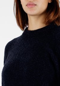 Maglione lavorato a maglia blu navy con collo alto, realizzato in un tessuto morbido e testurizzato, dal taglio rilassato. Nessun motivo o accento visibile.