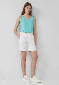 Türkiser ärmelloser Top, weiße Shorts mit Umschlägen, geflochtenem Gürtel und weißen Sneakers. Einfaches Design mit glatter Textur und ohne sichtbare Muster.