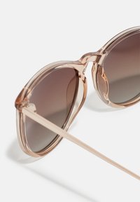 Pink-tinted sunglasses with gradient dark lenses, round frames, and thin arms; smooth texture with a glossy finish.