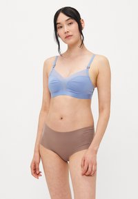 Lyseblå trådløs BH med mesh-detaler; glatt stoff; myke kopper. Brune sømløse truser med lav midje design. Rent, minimalistisk stil.