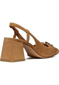 Tacco slingback in suede color tan con tacco spesso triangolare, punta aperta, decorazioni sul davanti e cinturino alla caviglia regolabile.