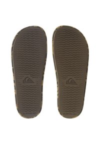 Semelles de tongs en caoutchouc brun avec un motif camouflage, dotées d'une texture ondulée pour l'adhérence et d'un logo de marque au talon.