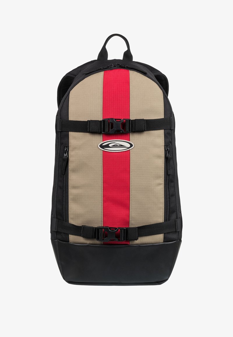 Sac à dos avec un design rayé beige et rouge, des bretelles et des accents noirs, présentant un fond robuste et une boucle avant fonctionnelle.