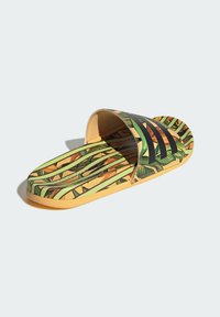 Sandal med slidestykke, der har et grønt og gult tropisk bladmønster, sorte striber på overdelen, samt en polstret sål og en solid gummisål.