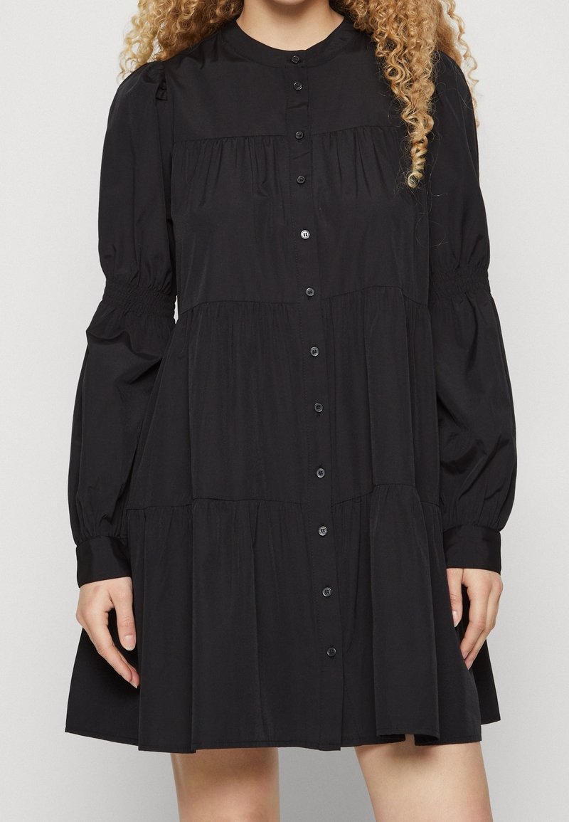 Black button-down dress with long puff sleeves, gathered bodice, and tiered skirt. Made of smooth fabric, featuring a classic collar and discreet buttons.