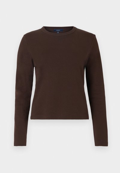 Καφέ μπλούζα με μακριά μανίκια από μαλακό βαμβάκι, με στρογγυλή λαιμόκοψη και εφαρμοστή γραμμή. Απλός σχεδιασμός χωρίς σχέδια ή διακοσμητικά στοιχεία.