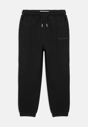 Zwarte sweatpants van zacht materiaal met een elastische tailleband, zijzakken en gescofte enkels. Voorzien van een subtiele logo aan de zijkant.