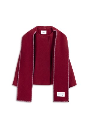 Wrap rouge en mélange de laine avec un design ouvert à l'avant. Présente des coutures blanches contrastantes le long des bords. Étiquette visible sur le côté droit.