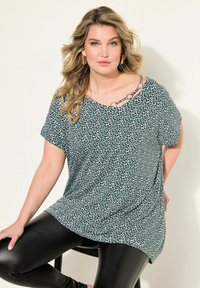 Top de manga corta en estampado animal verde y negro, con escote redondeado y adornos de metal. Fabricado en una tela suave con un ajuste relajado.