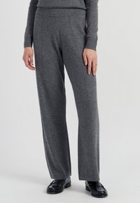Graue, weit geschnittene Hosen aus einem weichen Stoff mit einem gerippten Bund. Sie verfügen über subtile Seitennähte und eine gleichmäßige, glatte Textur.