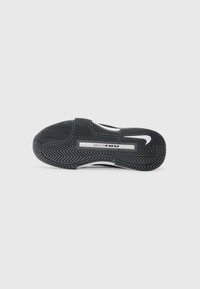 Crni gumeni đon tenisica sa ribljim kostima, sa bijelim Nike logotipom i vidljivim dijelom za ublažavanje Air Zoom.