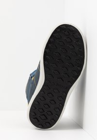 Sneaker blu con tomaia in pelle testurizzata, suola in gomma bianca e accenti di cucitura gialla. La suola presenta un motivo a rombi per una migliore aderenza.
