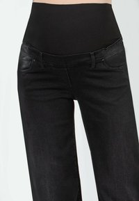 Schwarze Jeans mit hohem elastischen Bund, ausgestattet mit zwei Vorderaschen und einer glatten Textur. Entwickelt für Komfort und Passform.