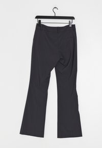 Pantalon évasé gris foncé avec une texture lisse, doté d'un devant plat, de deux poches arrière et d'un crochet pour le suspendre.