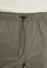 Grey drawstring shorts feature an elastic waistband, a side pocket, and a smooth texture with contrasting stitching details.