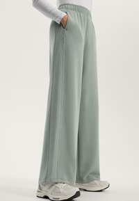 Ljust gröna vida byxor i mjukt tyg med sidofickor och ribbade detaljer. Matchas med vita och grå sportskor.