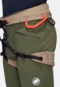 Groene klimspijkerbroeken met een beige tailleband en oranje accenten. Kenmerken zijn onder andere een klein ritsvakje en verstelbare banden. Logo zichtbaar.