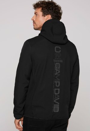 Sort hættetrøje lavet af tekstureret stof, med et lodret logo print. Designet er tætsiddende med en glat finish.