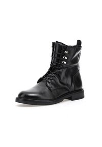 Bottine noire en cuir avec laçage devant et œillets en métal, talon bas et bout rond lisse sur fond blanc.