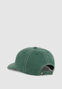 Vihreä puuvillainen baseball-lippis, jossa valkoiset tikkauslangat, säädettävä hihna ja kuudella ilmanventilaatioaukolla kruunussa. Sivussa logo-tagi.