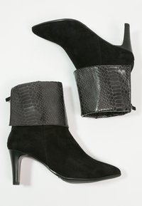 Botas de ante negras hasta el tobillo con un puño de imitación de cuero con patrón de reptil y un tacón cónico. Acabado brillante en el puño.