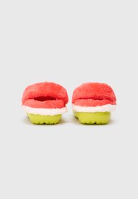 Dwa otwarte klapki z puszystym koralowym wykończeniem i białym wykończeniem. Podeszwa jest w jasnym zielonym kolorze z teksturowanym gripem. Miękka i luksusowa konstrukcja.