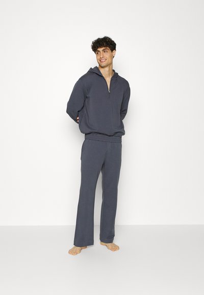 Conjunto de sweatshirt com capuz e calças em tecido cinza escuro. A sweatshirt apresenta um zíper parcial; as calças têm uma cintura elástica e pernas retas.