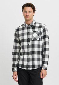 Zwart-wit geruite overhemd met lange mouwen, knoopsluiting aan de voorkant en een borstzak met een diagonaal patroon. Katoenen stof, casual ontwerp.